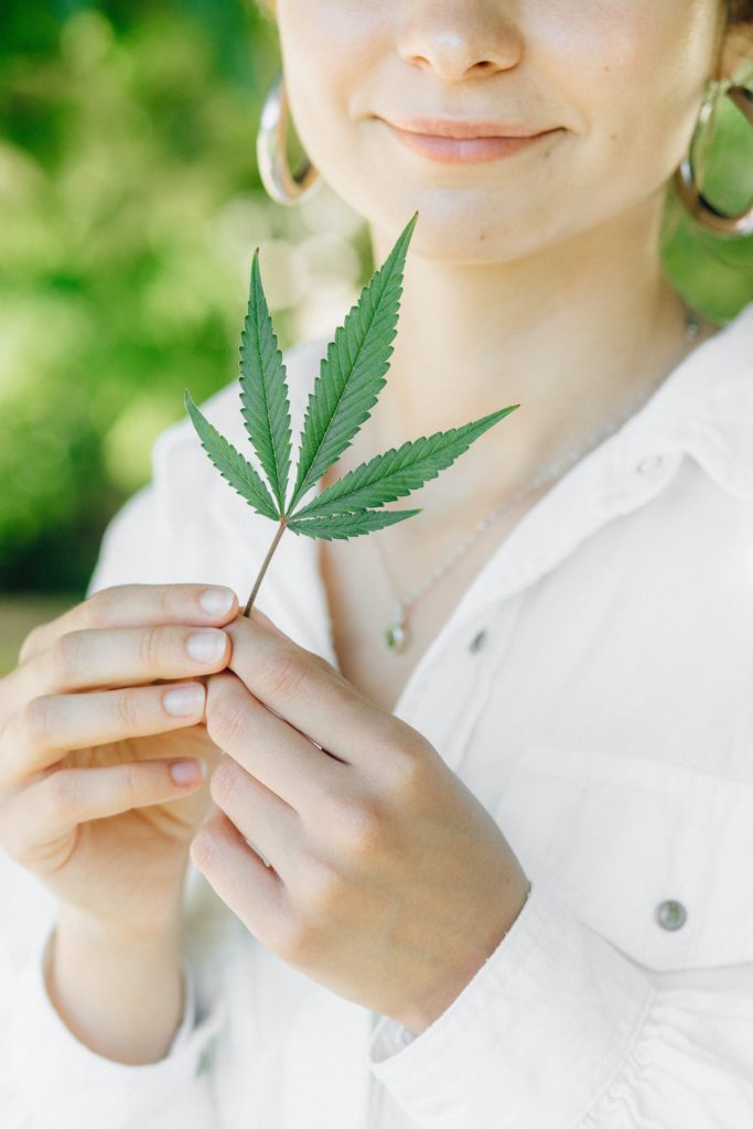 woman holding a cannabis leaf